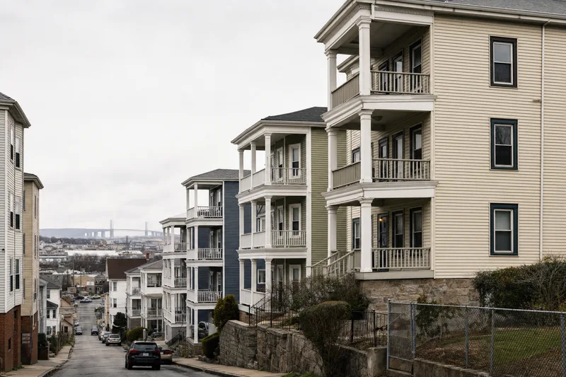 Cascading three-story porches on a hilly Fall River street of pre-1978 triple-deckers